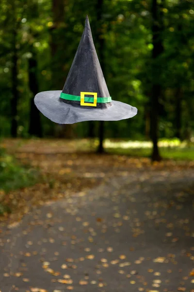 Sombrero de bruja de papel colgando en el aire por encima del camino en el parque de otoño — Foto de Stock