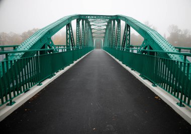 Kimsenin yürümediği sisli bir sonbahar sabahında yeşil köprü. 