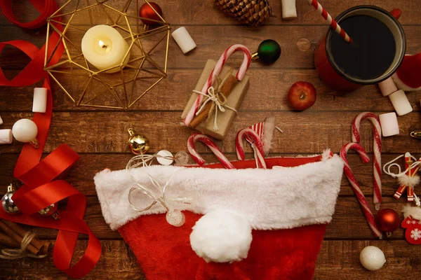 Sweets and gifts are in a Christmas hat on the table. — Stock Photo, Image