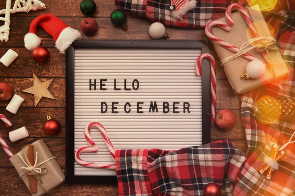 Merhaba yazan bir tahta. Aralık Noel oyuncakları ve baston şekerler.