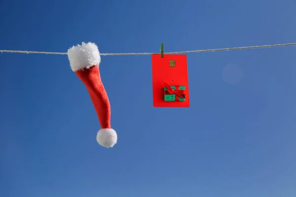 Close-up little Santa Claus hat and a credit card with a picture hanging — Stock Photo, Image