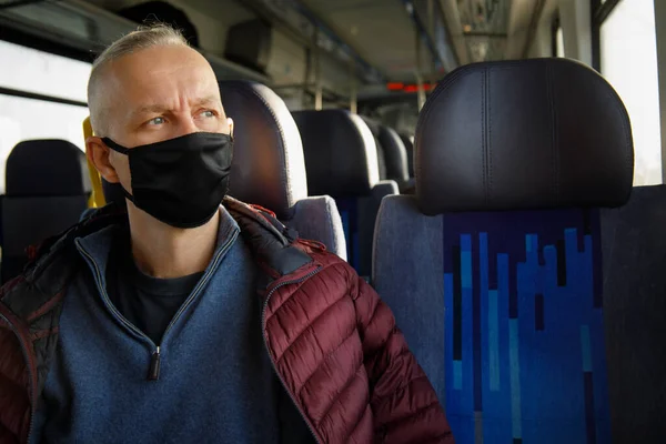  Adam hijyenik kısıtlamalar altında siyah bir maske takarak trende seyahat ediyor.