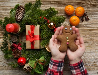  Elleri zencefilli kurabiye tutan adam. Noel çelengi ve mandalina yakınında..
