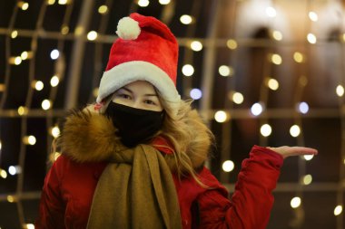 Noel Baba şapkası ve siyah maskeli genç kız yeni yıl sokağının yakınında. 