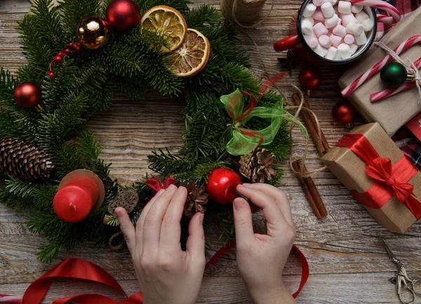 Decorazione domestica di Natale, mani femminili che tengono una ghirlanda, fatte a mano Immagini Stock Royalty Free