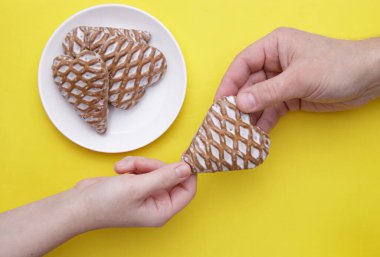 Kırpılmış resimli kız eli, adama kalp şeklinde zencefilli ekmek veriyor. 