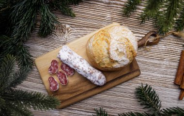 Ekmek ve sosis tahta bir tahtanın üzerinde yatar. köknar dallarıyla çevrili. 