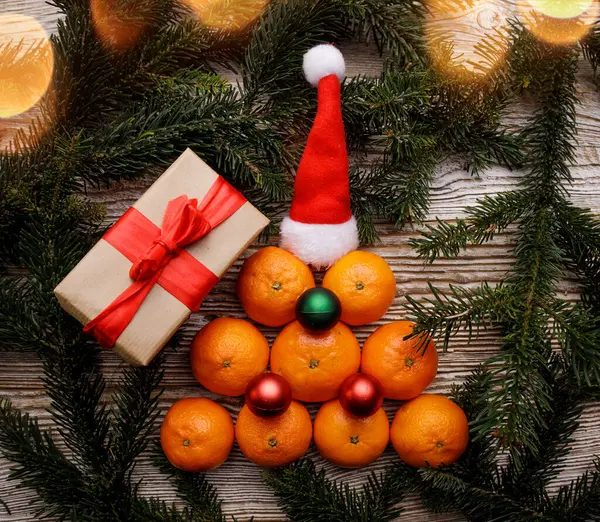 Tangerines folded on a table in the shape of a Christmas tree with decorations . — Stock Photo, Image