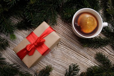 Kırmızı kurdeleli hediye kutusu ve sıcak kokulu bir bardak.