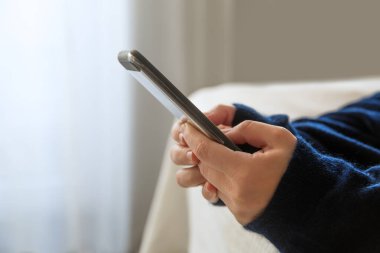 Akıllı telefonlu kız elleri yatağın üzerine uzanır. 