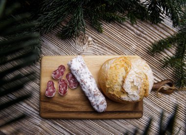 Ekmek ve sosis tahta bir tahtanın üzerinde yatar. köknar dallarıyla çevrili. 