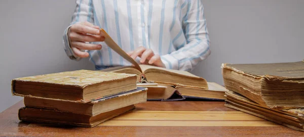 the hand of an invisible person leafs through the pages of old book.