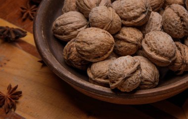 Kaçık. Koyu ahşap bir masada, toprak kabının içindeki cevizler.. 