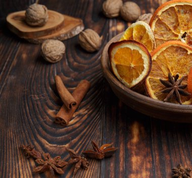 Eski bir ahşap masa üzerinde doğal portakal parçaları, anason yıldızları ve cevizler.