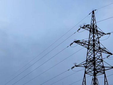 Mavi gökyüzüne karşı yüksek voltajlı kabloları olan demir sütun. iyi akşamlar.