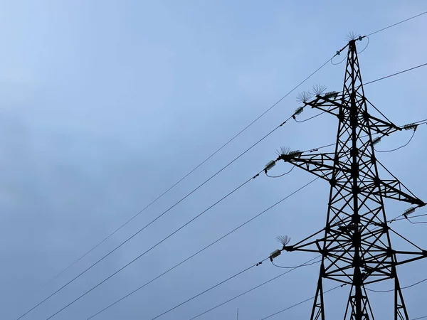 Mavi gökyüzüne karşı yüksek voltajlı kabloları olan demir sütun. iyi akşamlar.