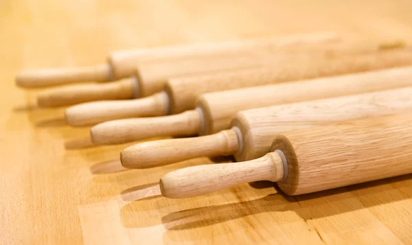 Rouleaux à rouler en bois pour rouler la pâte reposent en rangée sur une table en bois — Photo