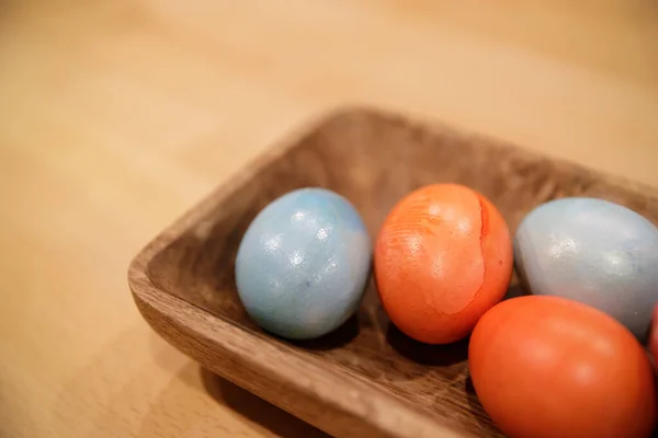 Several painted in different color of chicken eggs lie in a wooden tray — Stock Photo, Image