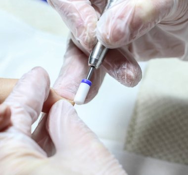 Güzellik salonundaki patronun elleri müşteriye manikür yapıyor.