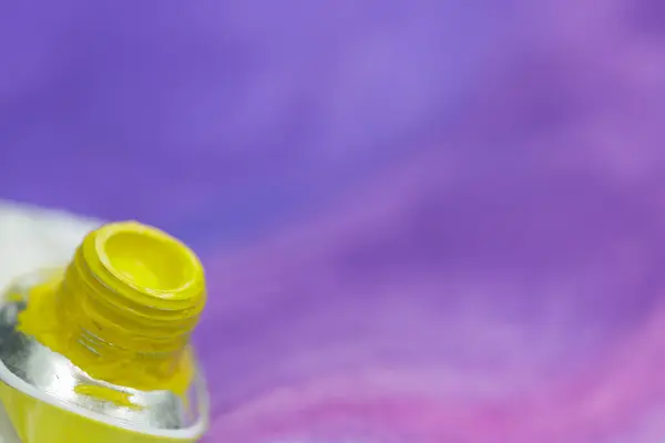 Tube Aquarellfarbe gelb vor dem Hintergrund violett bemalten Blattes — Stockfoto