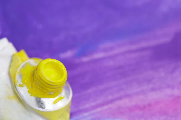 Трубка акварельної жовтої фарби на фоні фіолетового пофарбованого листа — стокове фото