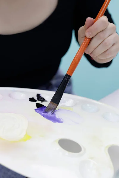 Рука студентки художньої школи молодої дівчини, яка набирає фарбу на пензлі — стокове фото