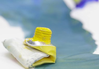 Mavi boyalı yaprağın arka planına sarılı suluboya boya tüpü