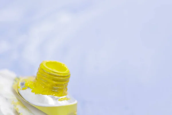 Трубка акварельної жовтої фарби на фоні синього пофарбованого листа — стокове фото