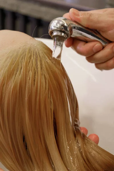 Cabeleireiro detém rega e água derrama o cabelo do cliente — Fotografia de Stock