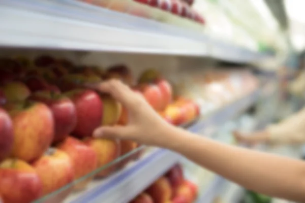 Abstrato azulado de mulher mão pegar maçãs de supermercado sh — Fotografia de Stock