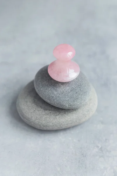 Pembe Gua Sha yüz masajı ve yüz bakımı aleti. Rose Quartz gua sha mashroom şekil taş gri taş piramit üzerinde beton zemin. Yaş karşıtı, yüz yogası, kaldırma ve tonlama tedavisi. Anlaşıldı.
