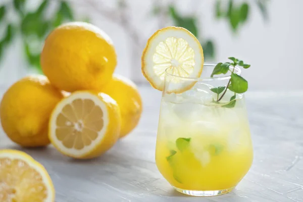 Citronnade glacée aux agrumes dans le verre avec tranche de citron et feuilles de menthe décoration sur table en marbre sur fond naturel — Photo