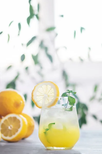 유리잔에 레몬 조각과 레몬 열매가 담긴 박하 잎을 넣은 싱싱 한 레모네이드 — 스톡 사진
