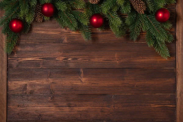Новорічний та різдвяний макет з гілками ялинки та червоними та золотими прикрасами на дерев'яному фоні — стокове фото