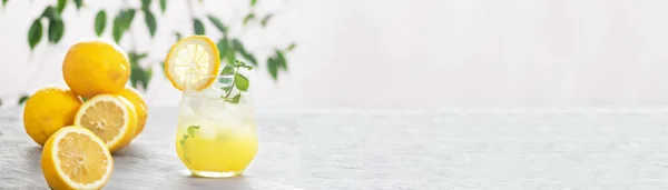 Citronnade glacée aux agrumes dans le verre avec tranche de citron et feuilles de menthe décoration sur table en marbre sur fond naturel — Photo