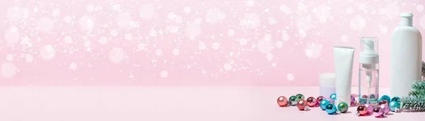 Banner with christmas beauty skin care cosmetic products with decoration balls on the pink background. Make-up products