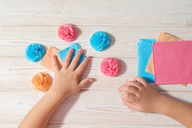 Dümdüz uzanmış çocuk elleri kağıttan çiçekler yapıyor. Küçük çocuk eli ile yakın plan.