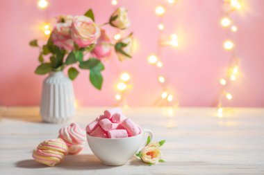 Çiçeklerle süslenmiş bayram şenlikli romantik masa ve şekerleme dolu bir fincan.