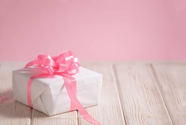 Açık ahşap masada pembe kurdeleli güzel beyaz kutu metin için kopyalama alanı ile