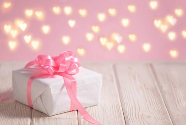 Açık ahşap masada pembe kurdeleli güzel beyaz kutu metin için kopyalama alanı ile