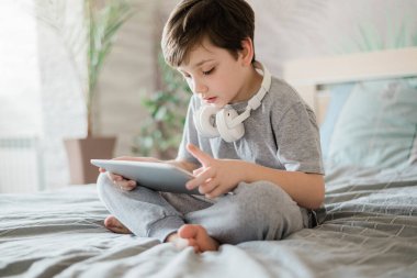 Mutlu çocuk evde yatakta yatıp bilgisayarla oynuyor ya da internetten kitap okuyor ve müzik dinliyor.