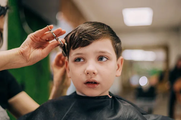 Стрижка для маленького мальчика, профессиональный парикмахер стрижется. Парикмахерская для детей — стоковое фото