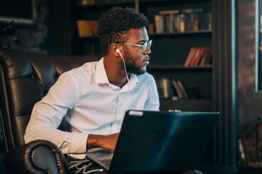 Dizüstü bilgisayarlı bir iş adamı. Neşeli genç Afrikalı işadamı dizüstü bilgisayarında bir şeyler yazıyor.