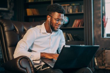 Dizüstü bilgisayarlı bir iş adamı. Neşeli genç Afrikalı işadamı dizüstü bilgisayarında bir şeyler yazıyor.