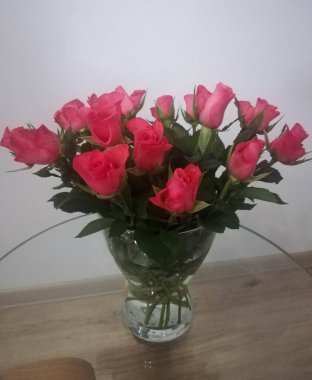 Cam sehpanın üzerine konmuş şeffaf cam vazodaki pembe güller. Bahar arkaplanı, çiçek duvar kağıdı.