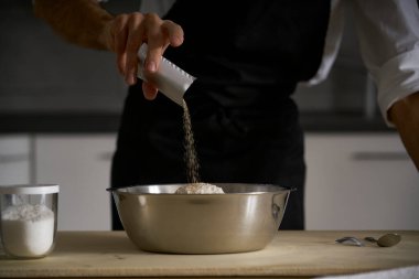 İnsan elleri ekmek, makarna, pasta ya da pizza yapmak için un hamuruna tuz ve maya ekler. Mutfağının ahşap masasında aşçı ev yapımı makarna geleneğini sürdürür..