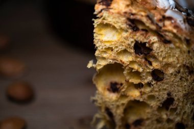 Panettone, tipik İtalyan noel pastası. Çikolata ve bademli. Arka planda panettone, yumurta, un ve çikolata yapımında kullanılan malzemeler var..