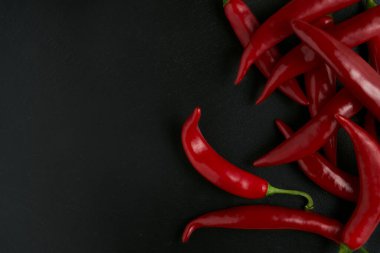 Arka planda siyah taş bir tabakta kırmızı biber, tariflerin ve yemeklerin hazırlanması için çiğ yemek.