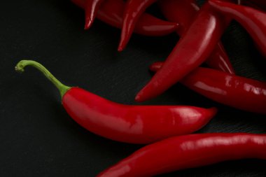 Arka planda siyah taş bir tabakta kırmızı biber, tariflerin ve yemeklerin hazırlanması için çiğ yemek.