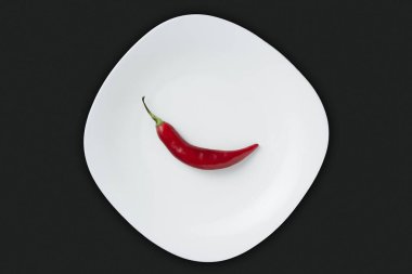 Siyah taş arka planda izole edilmiş kırmızı acı biber, baharatlı ve tutkulu tarifler için ideal malzeme.